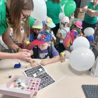 Pracownik Banku robiący brokatowe tatuaże przybyłym na Święto Spółdzielczości dzieciom