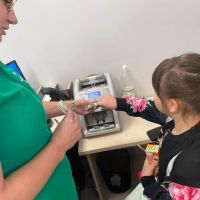 Pracownik Banku pokazujący dziewczynce funkcjonalności liczarki do banknotów