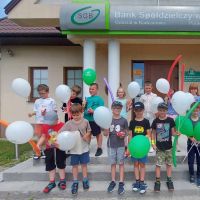 Dzieci pozujące z balonami przed budynkiem Punktu Kasowego w Starej Błotnicy