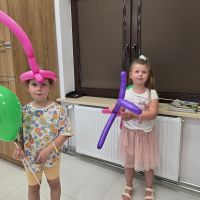 Dziewczynki pozujące z czapkami z balonów wykonanych przez pracowników Banku