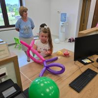 Dziewczynka pozująca z balonem pieskiem wykonanym przez pracowników Banku