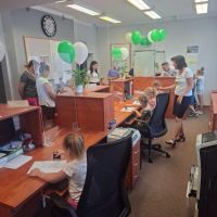 Sala operacyjna Banku z dziećmi siedzącymi za biurkami pracowników