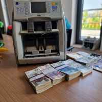 Zdjęcie przedstawiające liczarkę z banknotami