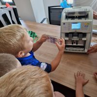 Chłopiec wkładający do liczarki banknoty