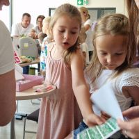 Dziewczynki wybierające wzory brokatowych tatuaży, które wykonają pracownicy Banku