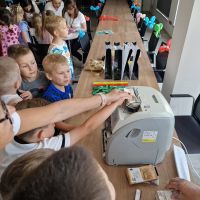 Dzieci obserwujący liczenie banknotów przez liczarkę