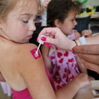 Pracownik Banku wykonujący brokatowy tatuaż na ramieniu dziewczynki