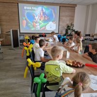 Dzieci siedzące przy stole konferencyjnym i słuchające opowieści o Króliku Filipie