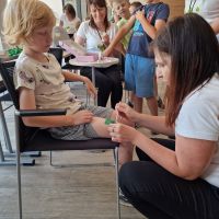 Pracownik Banku wykonujący chłopcu brokatowy tatuaż