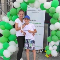 Pracownik Banku pozujący do zdjęcia pamiątkowego z chłopcem na ściance z balonów