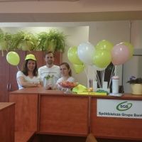 Pracownicy pozujący na tle kolorowych balonów i gadżetów z logo Banku