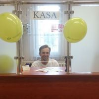 Uśmiechnięty Kasjer Banku na stanowisku pracy ozdobionym balonami
