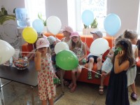 Dzieci trzymające kolorowe balony z logo Banku
