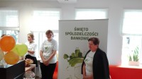Pani Prezes i pracownicy pozujący na tle plakatu Święta Spółdzielczości Bankowej