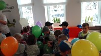 Dzieci siedzące na kanapie z balonami z logo Banku