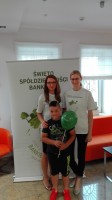Pracownicy pozujący z chłopcem trzymającym balon na tle plakatu Święta Spółdzielczości Bankowej