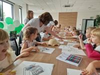 Pracownicy Banku pomagający dzieciom w kolorowaniu malowanek